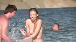 A mature woman is walking naked on the sunny beach