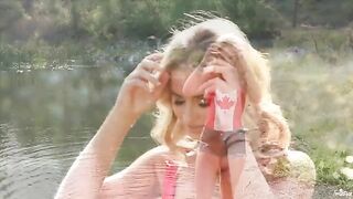 A beautiful blonde girl caresses herself on the lake’s shore