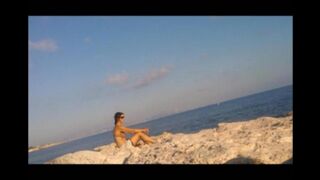 A young girl sunbathes naked on the beach, taking risks