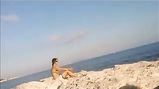 A young girl sunbathes naked on the beach, taking risks