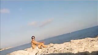 A young girl sunbathes naked on the beach, taking risks