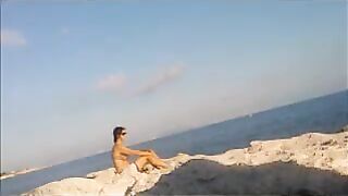 A young girl sunbathes naked on the beach, taking risks
