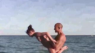 A group of acrobats perform without clothes on the sandy coast